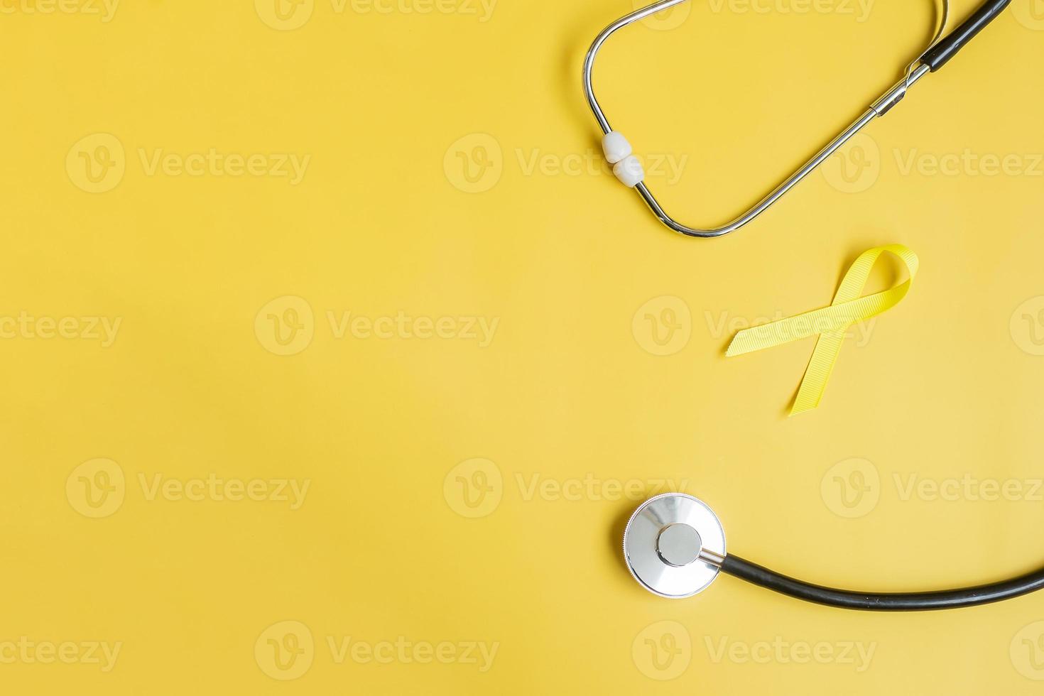 gelbes band und stethoskop auf gelbem hintergrund zur unterstützung von lebenden und kranken menschen. Tag der Suizidprävention im September, Monat des Bewusstseins für Krebs im Kindesalter und Konzept des Weltkrebstages foto