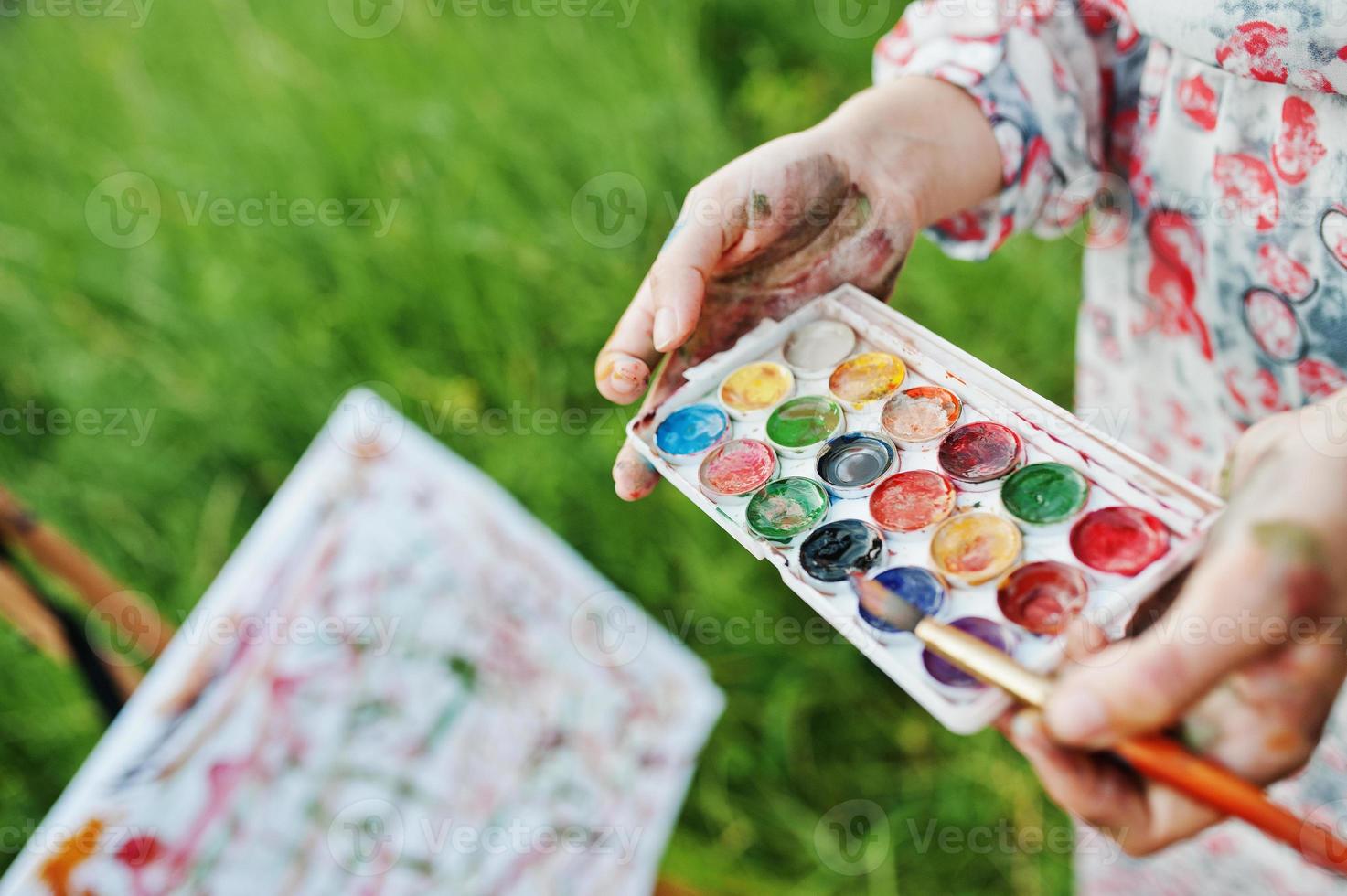 Nahaufnahme von weiblichen Händen, die Aquarellfarben und einen Pinsel halten, während sie in der Natur malen. foto