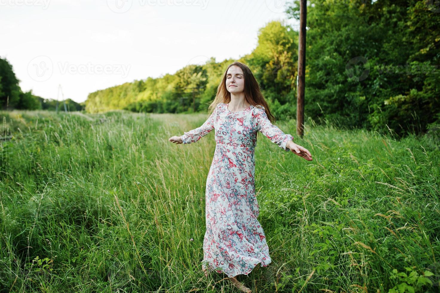 Porträt einer fabelhaften jungen Frau im Kleid, die im hohen Gras spazieren geht. foto