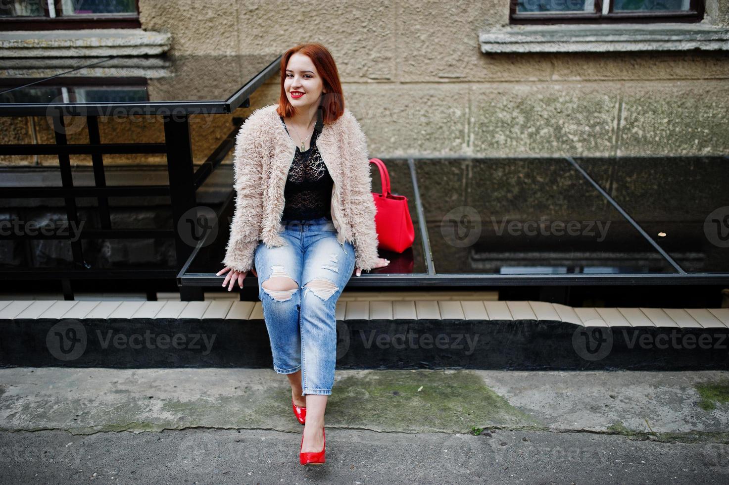 Rothaariges Mädchen mit roter Handtasche posierte auf der Straße der Stadt. foto