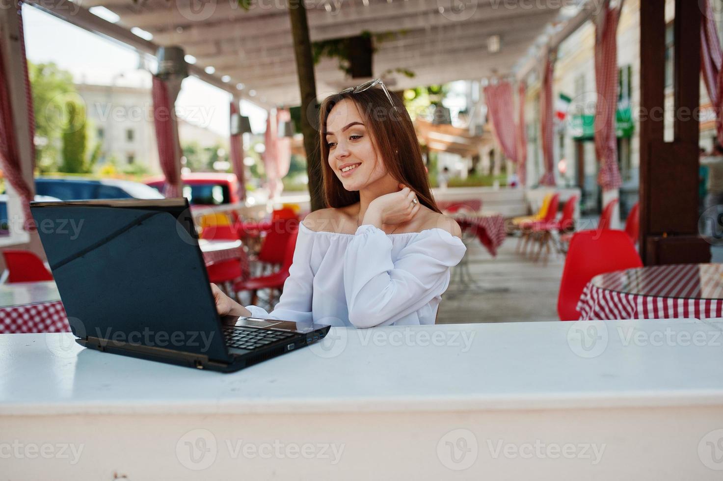 Porträt einer starken, unabhängigen, erfolgreichen Geschäftsfrau mit eleganter Freizeitkleidung und Brille, die in einem Café an einem Laptop arbeitet. foto