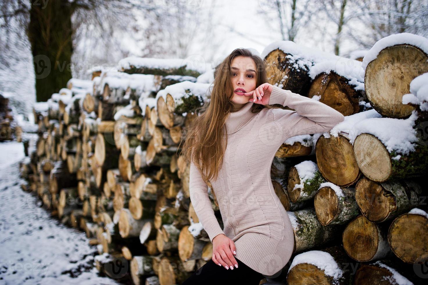 schönes brünettes Mädchen in warmer Winterkleidung. Modell auf Winterpullover in der Nähe von Baumstumpf. foto