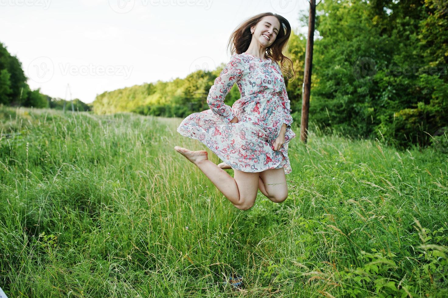 Porträt eines atemberaubenden jungen Mädchens im Kleid, das auf der Wiese springt. foto