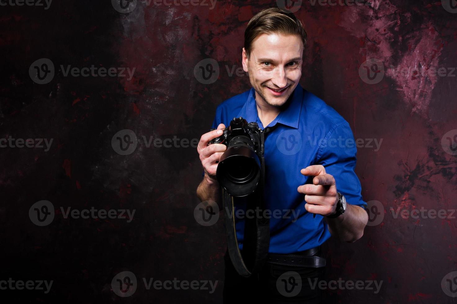 studioporträt eines stilvollen professionellen fotografenmannes mit kamera, tragen auf blauem hemd und krawatte. foto