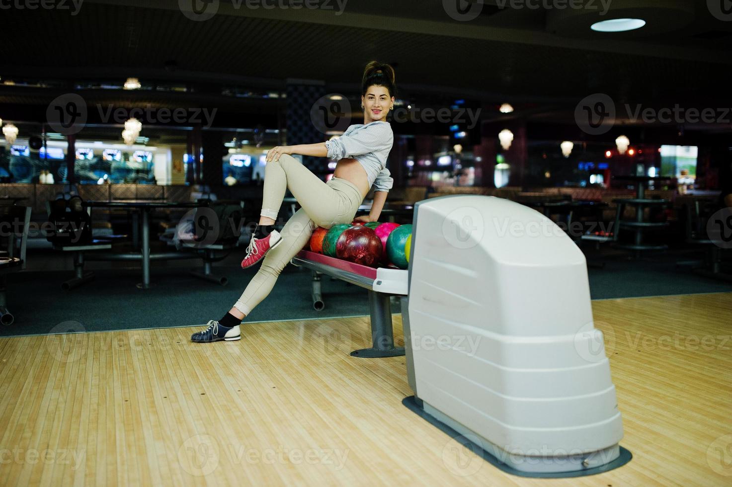 Mädchen mit Bowlingkugel auf der Gasse spielte im Bowlingclub. foto