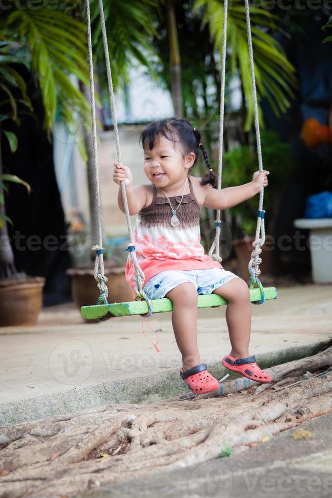kleines Mädchen spielen Schaukel im Garten foto