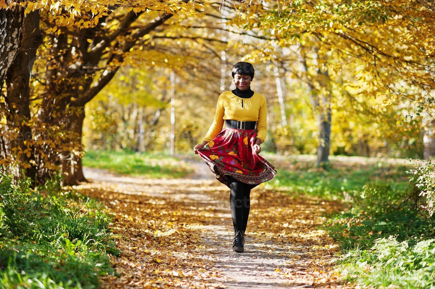 afroamerikanisches Mädchen im gelben und roten Kleid im goldenen Herbstpark. foto