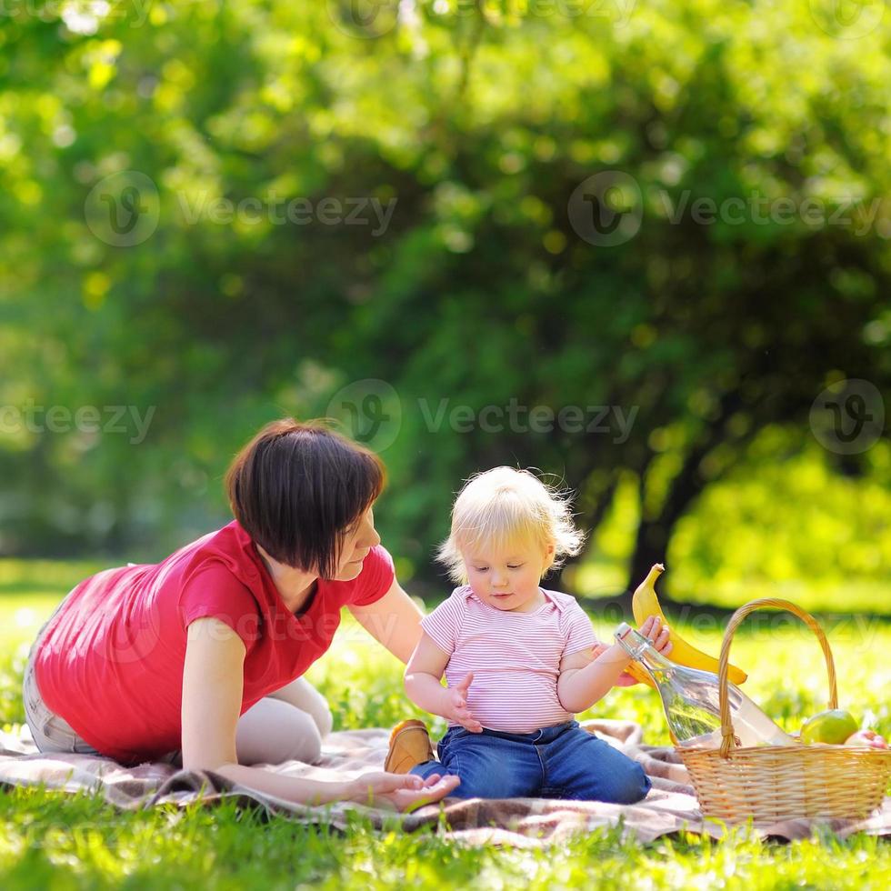 Frau mittleren Alters und ihr kleiner Enkel im sonnigen Park foto