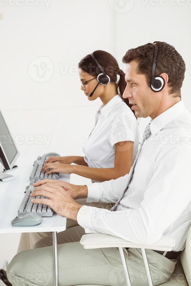 Geschäftsleute mit Headsets, die Computer im Büro verwenden foto