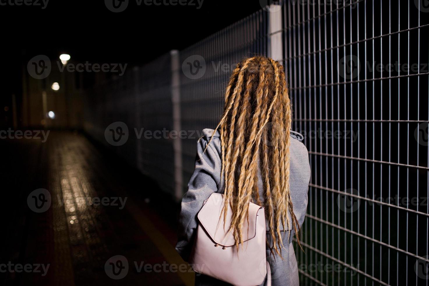 Mädchen mit Dreadlocks, die nachts auf der Straße der Stadt spazieren gehen. foto