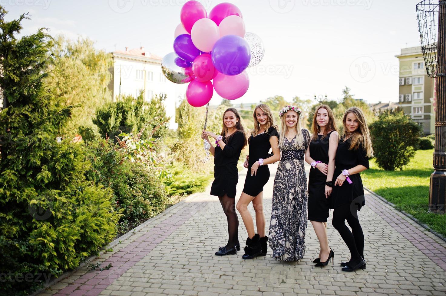 Fünf Mädchen tragen beim Junggesellinnenabschied Schwarz mit Luftballons. foto