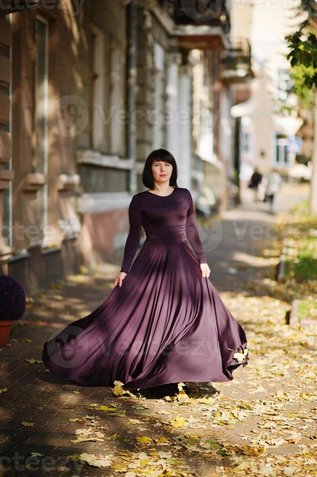 erwachsene brünette frau im violetten kleid auf herbstfallhintergrund. foto