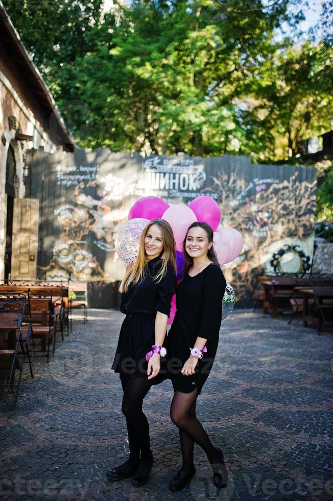 Zwei Mädchen tragen beim Junggesellinnenabschied Schwarz mit Luftballons. foto