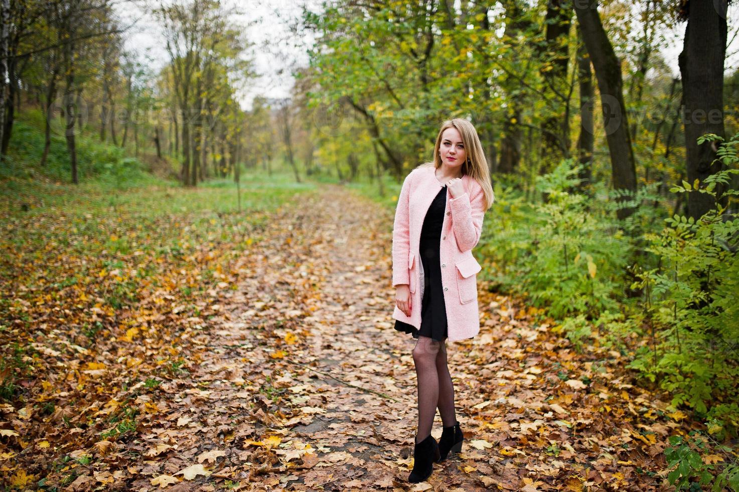junges blondes mädchen im rosa mantel posierte im herbstpark. foto