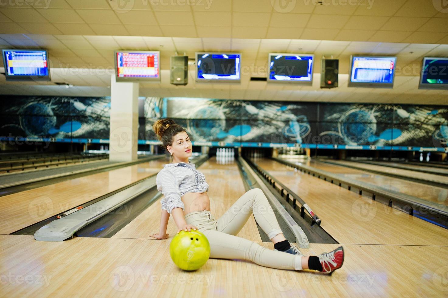 Mädchen mit Bowlingkugel auf der Gasse spielte im Bowlingclub. foto