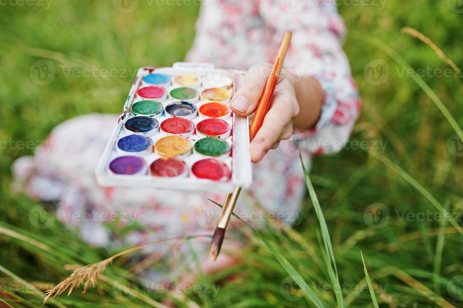 Nahaufnahme von weiblichen Händen, die Aquarellfarben und einen Pinsel halten, während sie in der Natur malen. foto