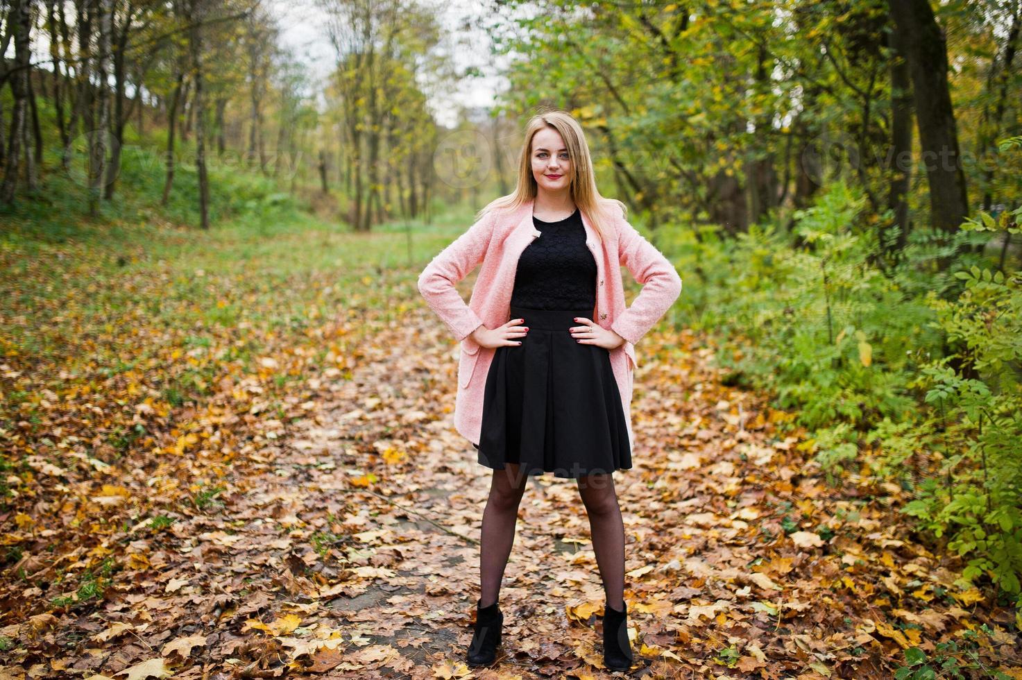 junges blondes mädchen im rosa mantel posierte im herbstpark. foto