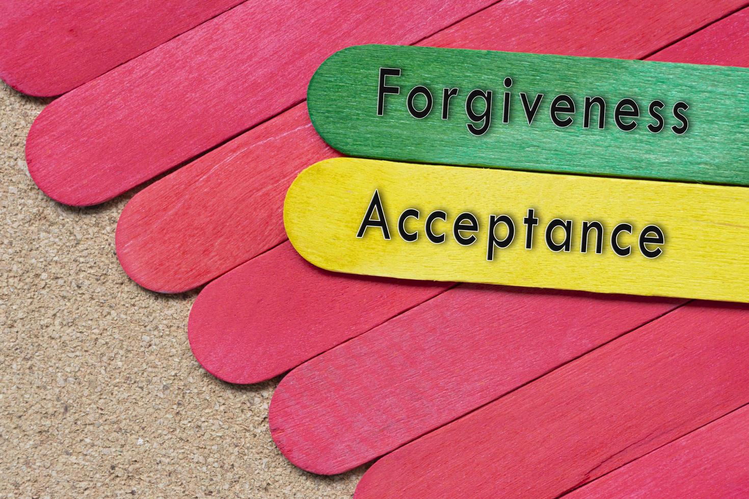 Vergebungs- und Akzeptanztext auf bunten Holzstäbchen auf Holzschreibtisch. foto