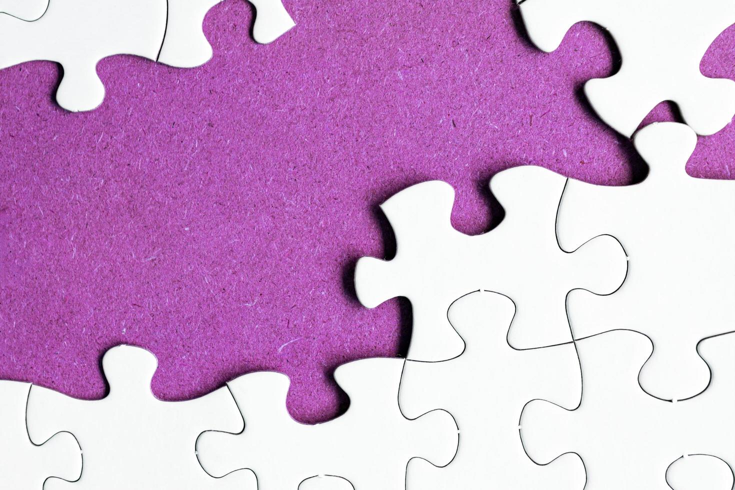 weißes Puzzle mit einigen fehlenden Teilen auf violettem Hintergrund. Platz kopieren. foto
