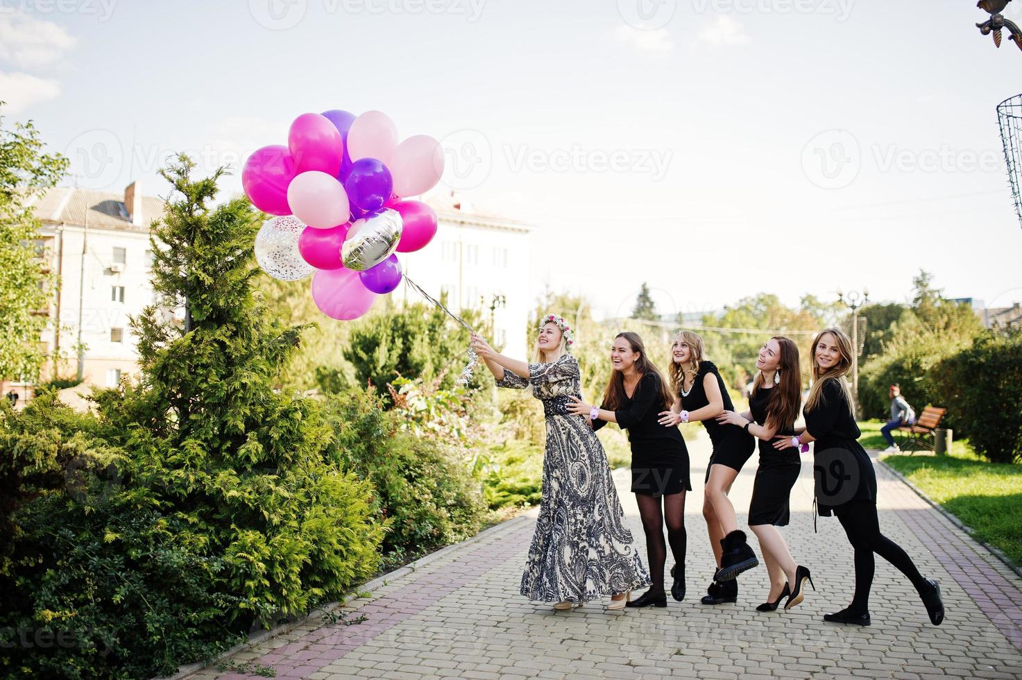 Fünf Mädchen tragen beim Junggesellinnenabschied Schwarz mit Luftballons. foto