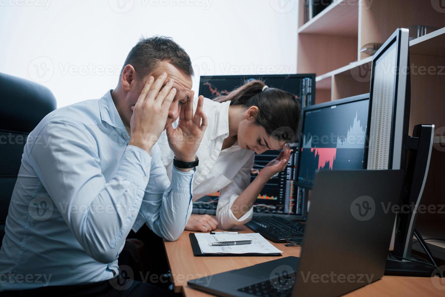 viel Geld verloren. Ein Team von Börsenmaklern führt ein Gespräch in einem Büro mit mehreren Bildschirmen foto