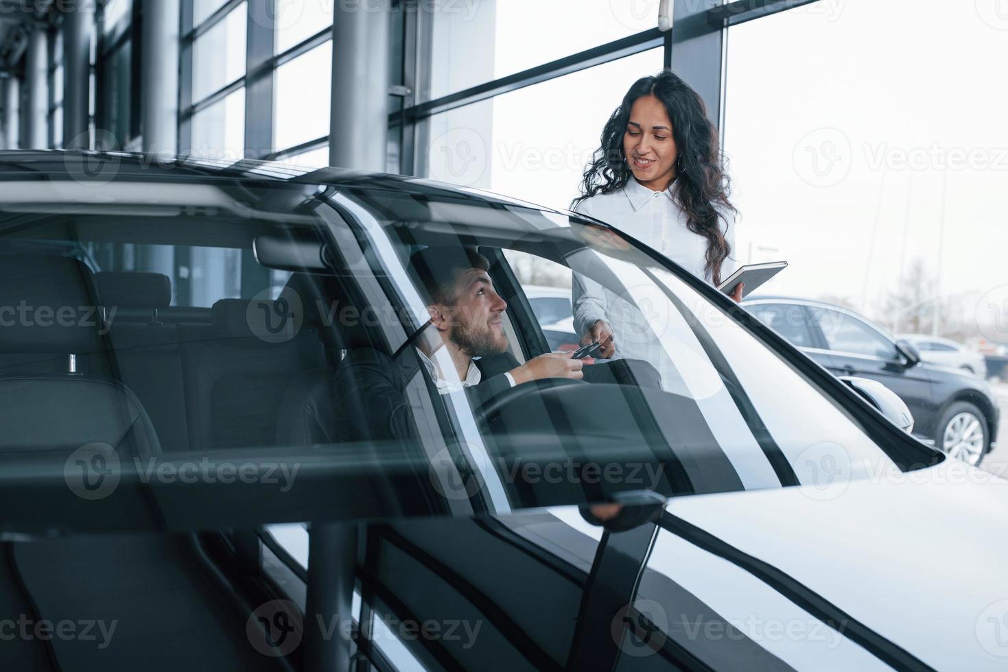 wie es sich für dich anfühlt. männlicher kunde und moderne geschäftsfrau im autosalon foto