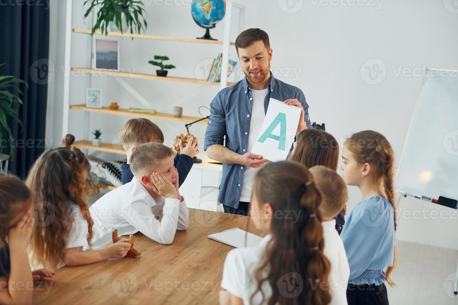 einen Brief zeigen. gruppe von kinderschülern im unterricht in der schule mit lehrer foto