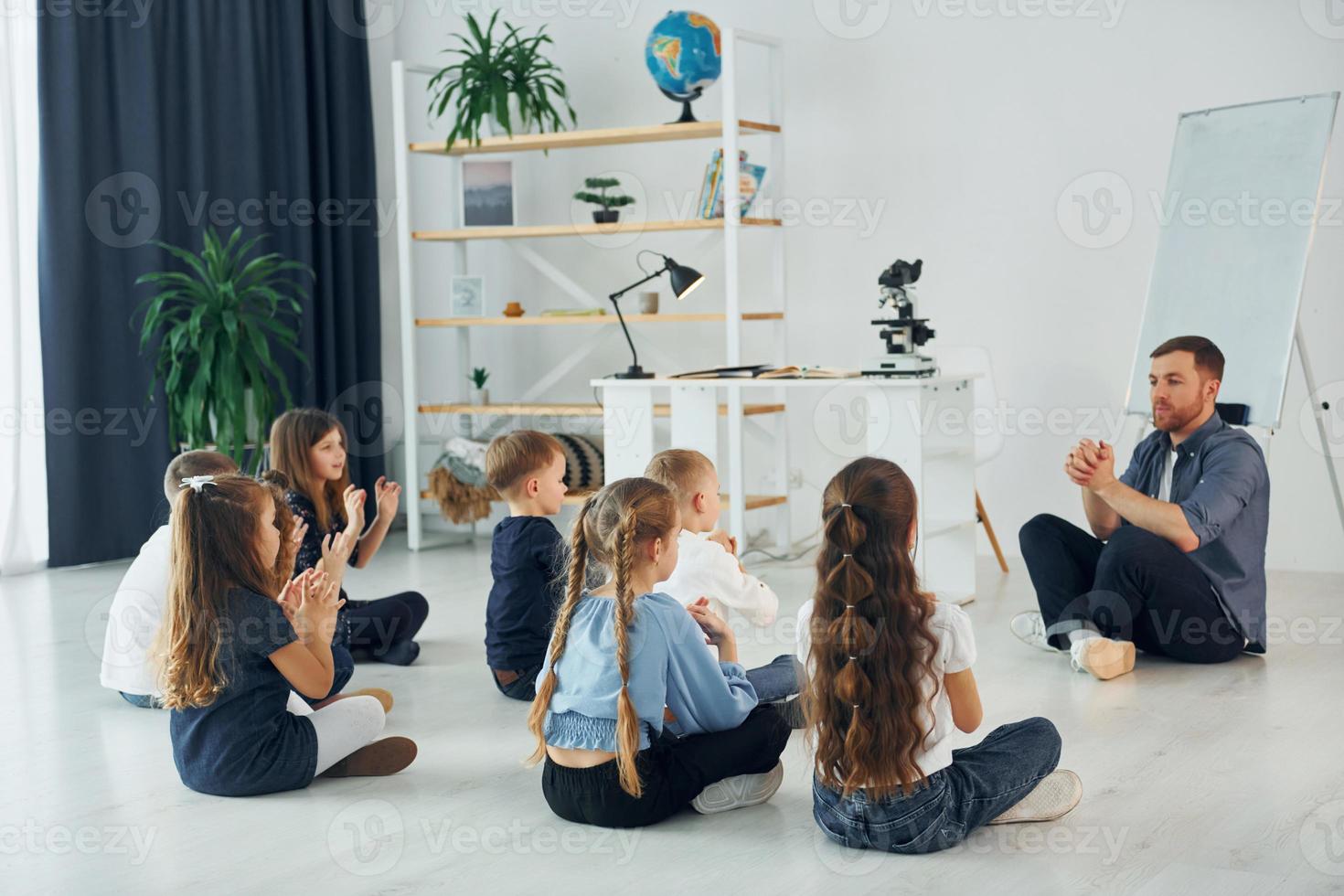 Mann lehrt Gestensprache. gruppe von kinderschülern im unterricht in der schule mit lehrer foto