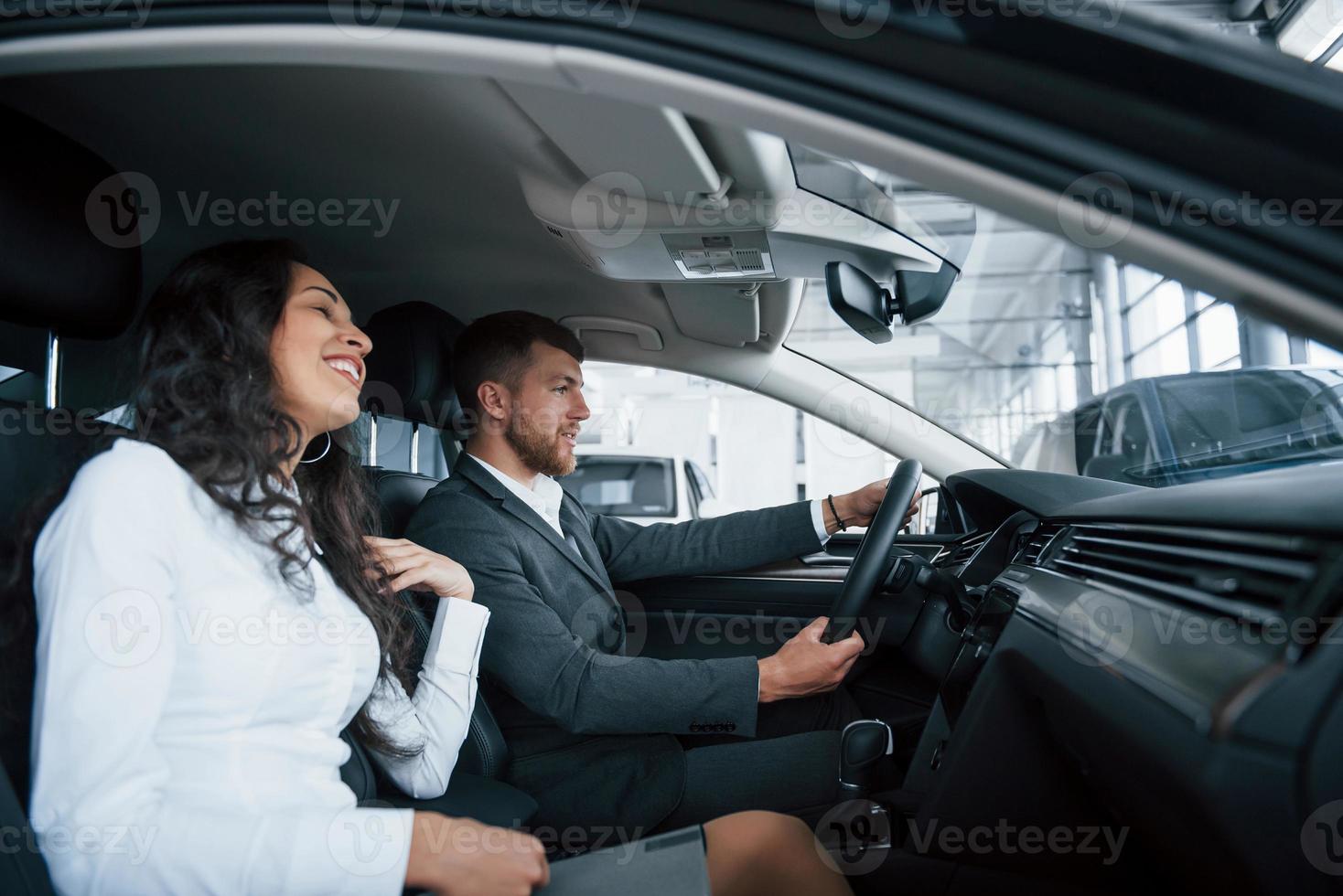 das ist dein Geschenk. Schönes erfolgreiches Paar, das im Automobilsalon  ein neues Auto ausprobiert 8682635 Stock-Photo bei Vecteezy