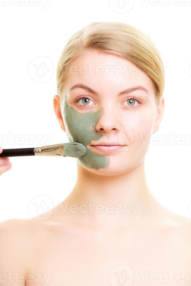Hautpflege. Frau, die Tonschlammmaske auf Gesicht anwendet. foto