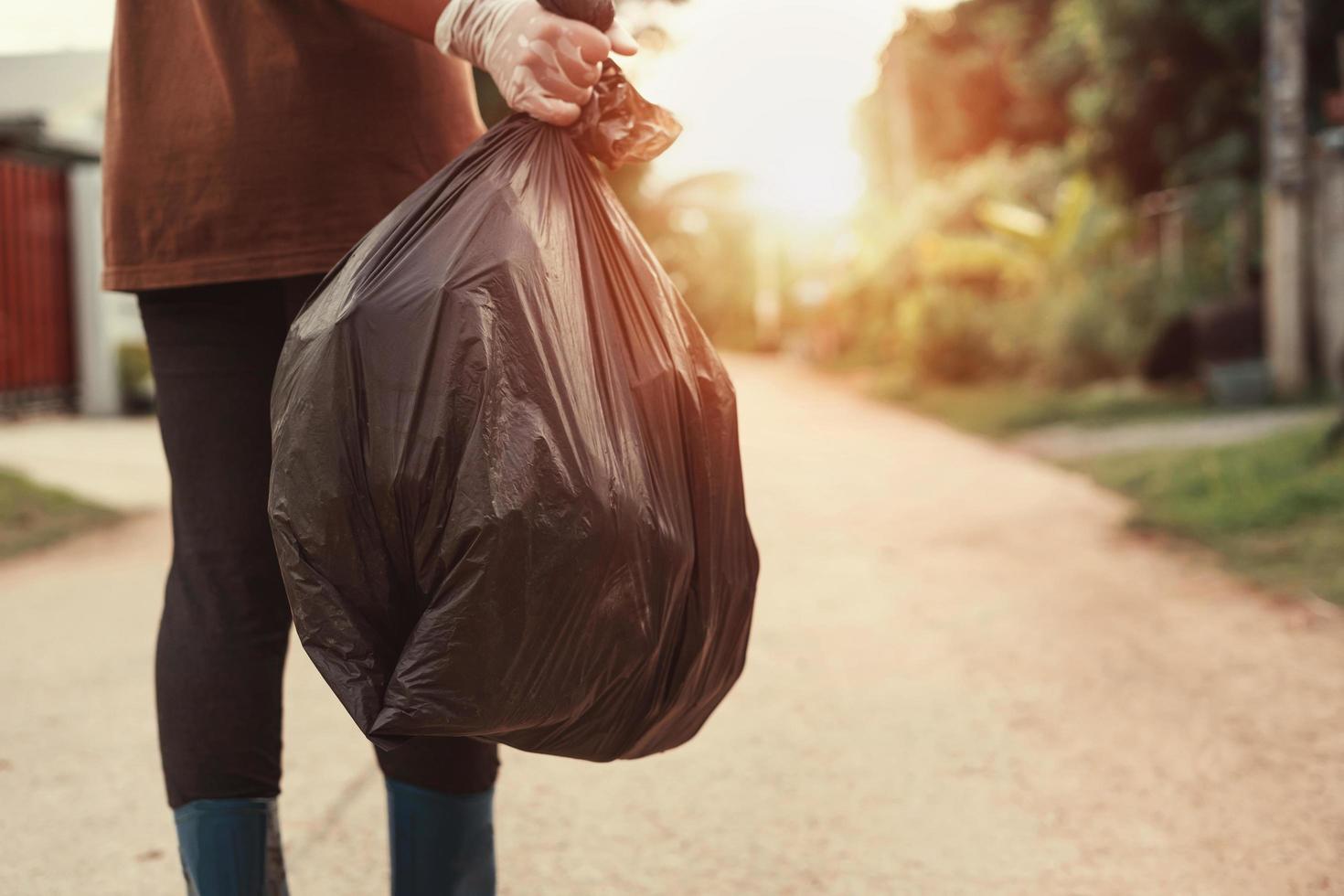 frauenhand, die müllbeutel zum recyceln in den müll hält foto