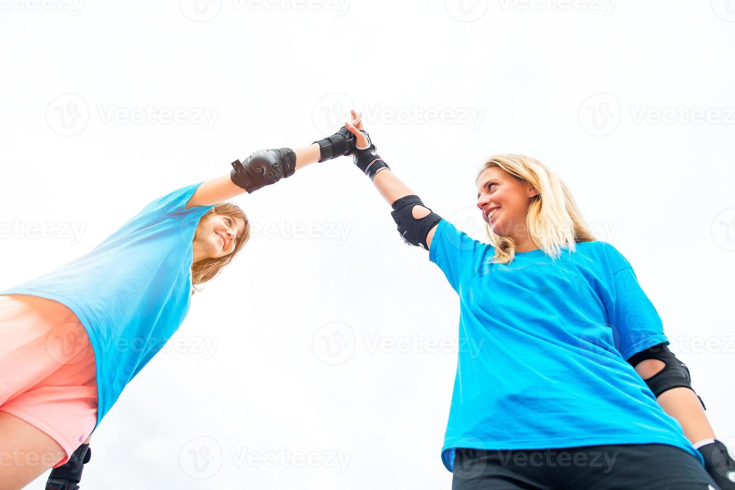 Zwei Sportmädchen in einem Tennis-Inline-Skate klatschen dir in die Hand foto
