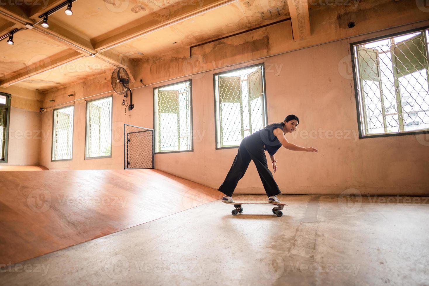 skater-frau, die skateboard in der sporthalle spielt, junge asiatische frau ist glücklich und macht spaß mit dem skateboarding-lebensstil in der stadt, jugendliche hipster-weibliche trendige mode foto