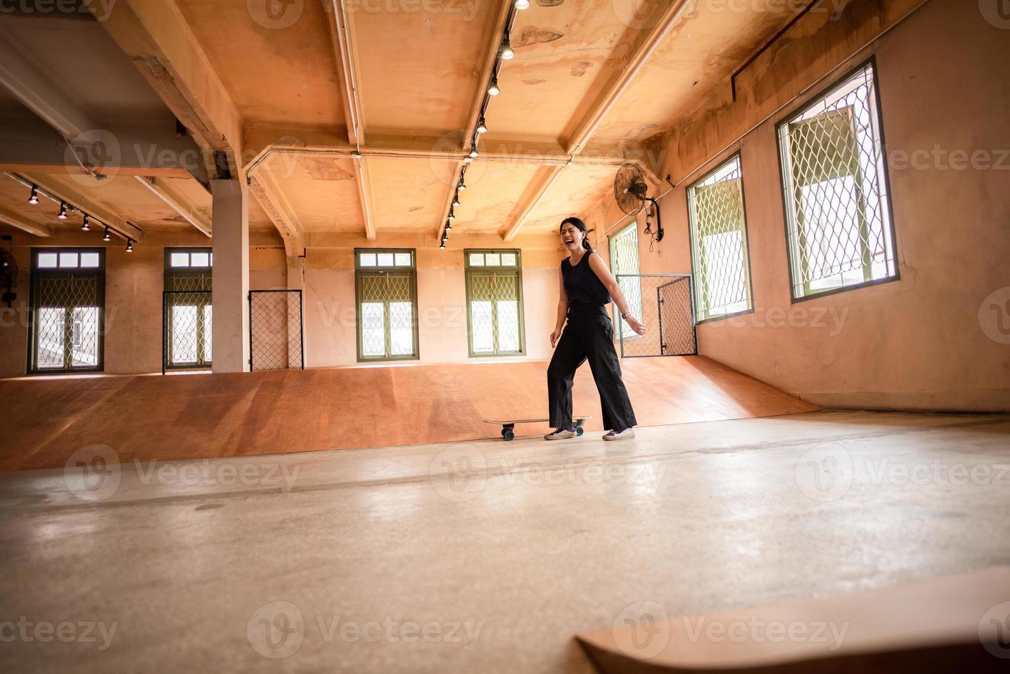 skater-frau, die skateboard in der sporthalle spielt, junge asiatische frau ist glücklich und macht spaß mit dem skateboarding-lebensstil in der stadt, jugendliche hipster-weibliche trendige mode foto