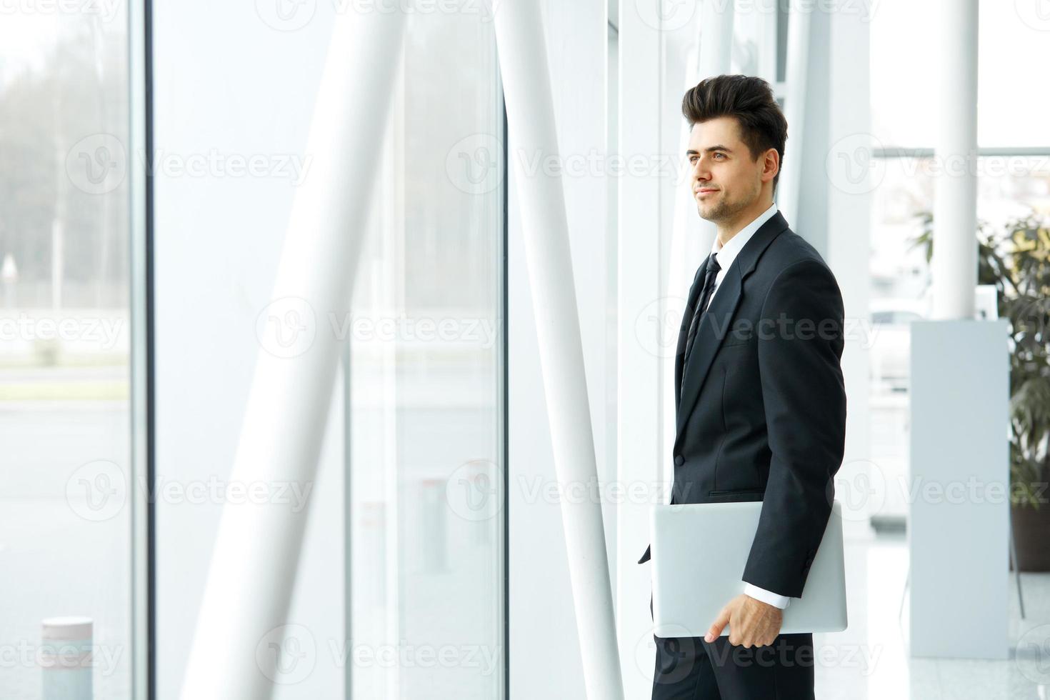 Geschäftsmann mit Laptop nahe dem Fenster, das an Zukunft denkt foto