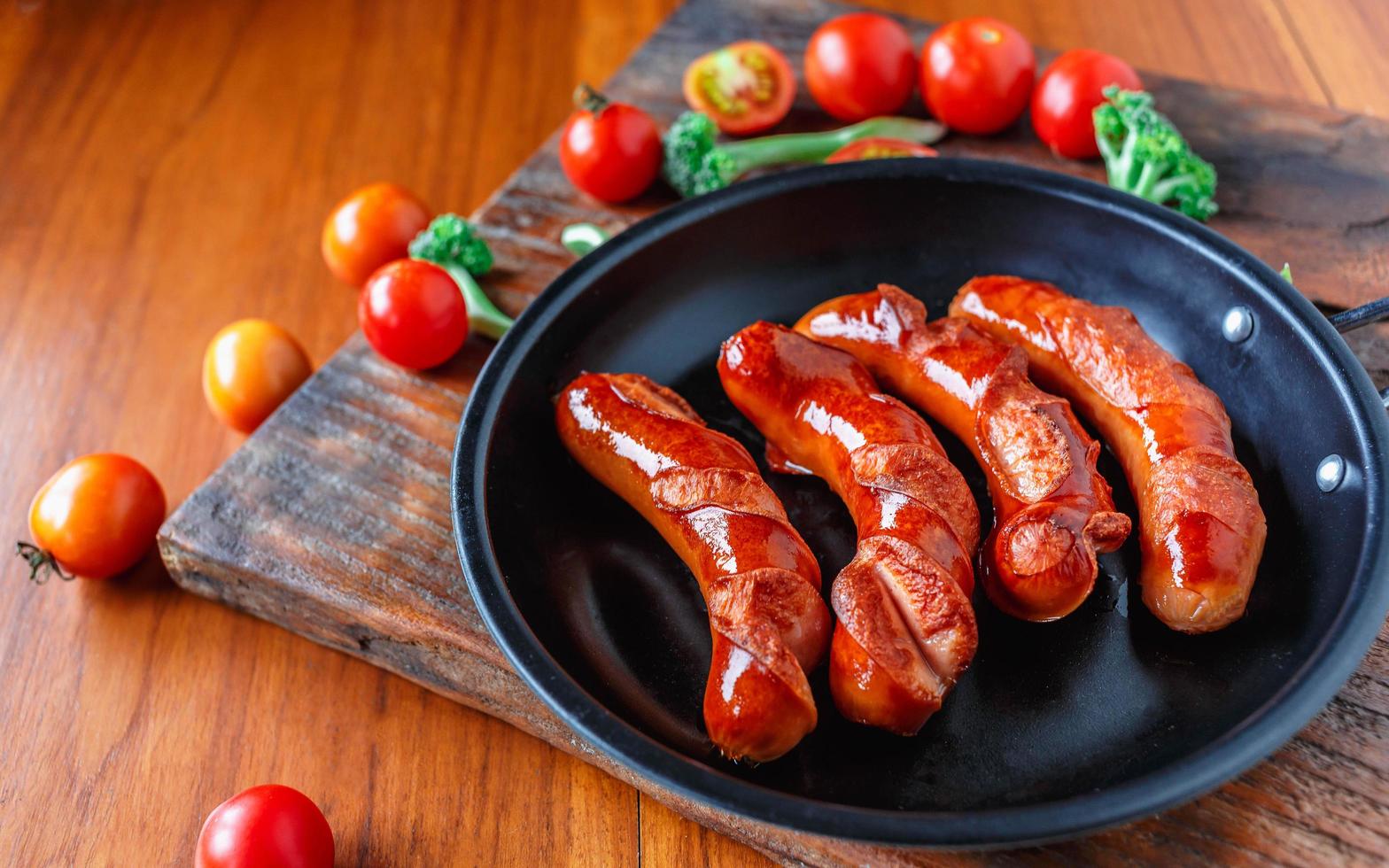 Bratwürste in einer Pfanne mit Tomaten und Brokkoli foto