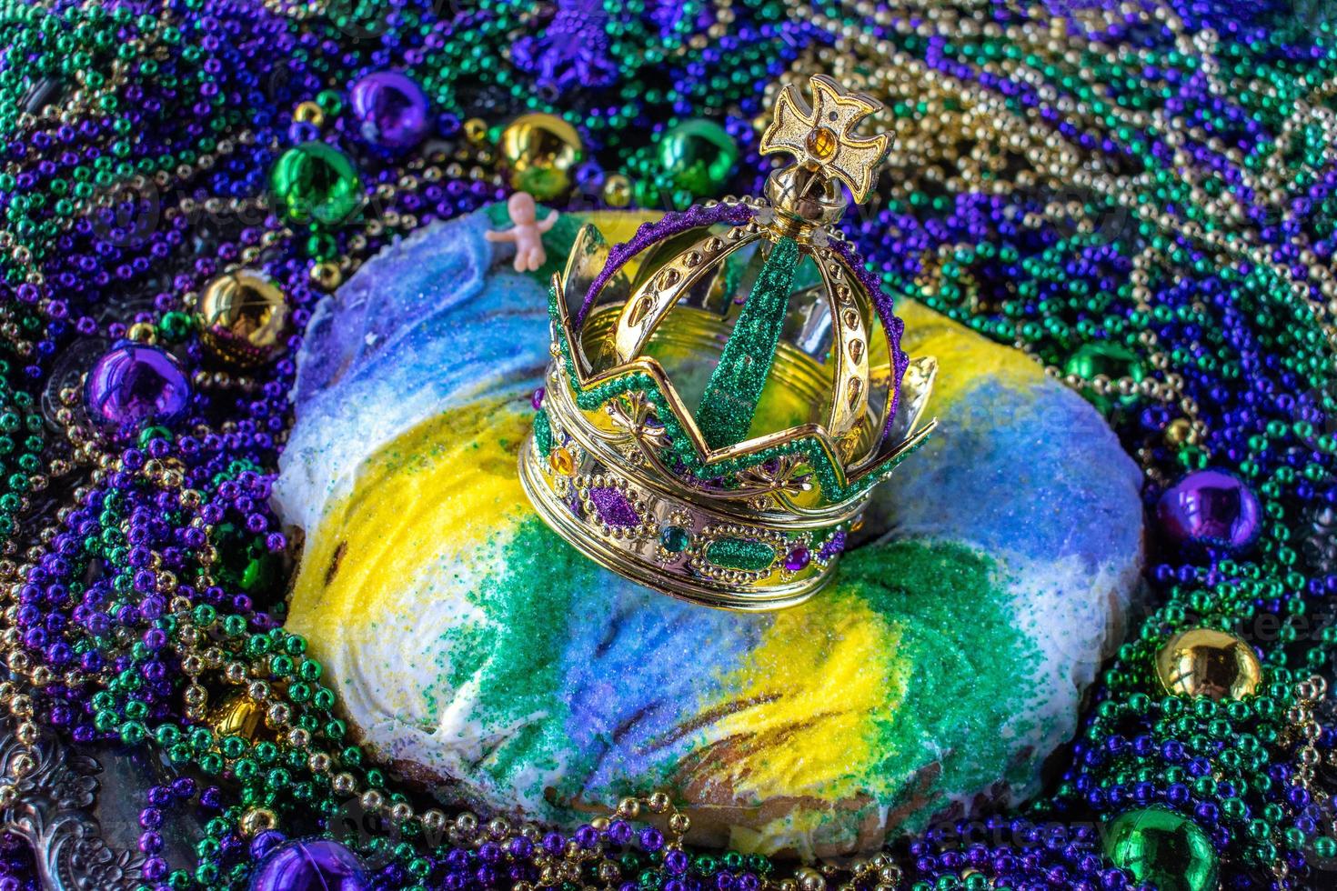 Mardi Gras King Cake mit Krone, umgeben von Perlen und Dekorationen foto