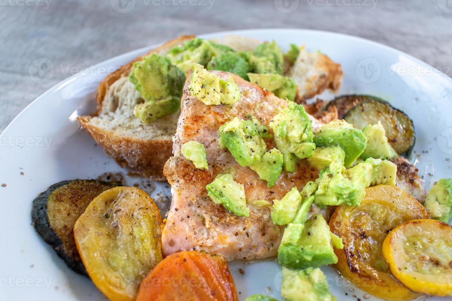 gesundes Tellergericht mit Lachs, Avocado und gegrilltem Gemüse foto