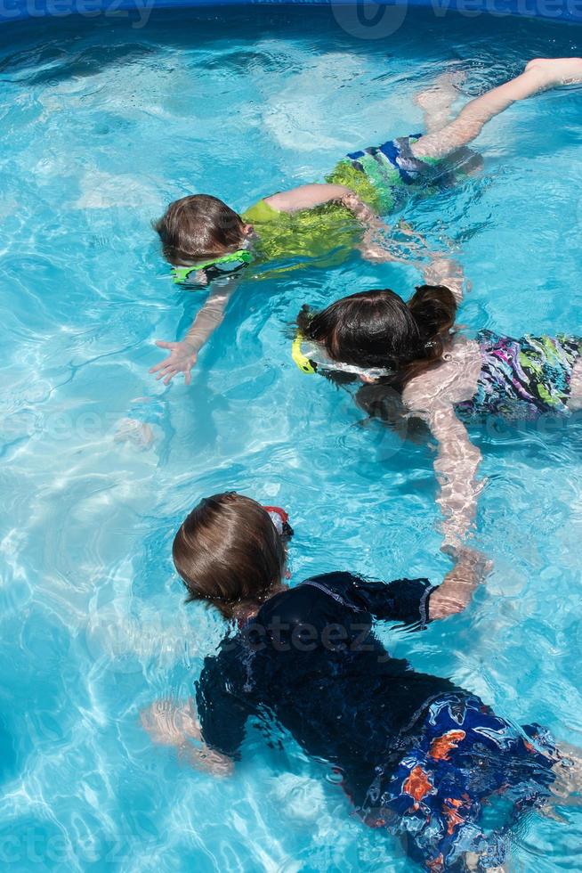 junge kinder halten sich unter wasser mit brillen im pool an den händen foto