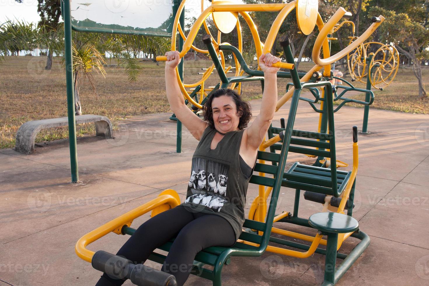 Reife Frau, die versucht, in einem Outdoor-Fitnesspark in Form zu kommen foto
