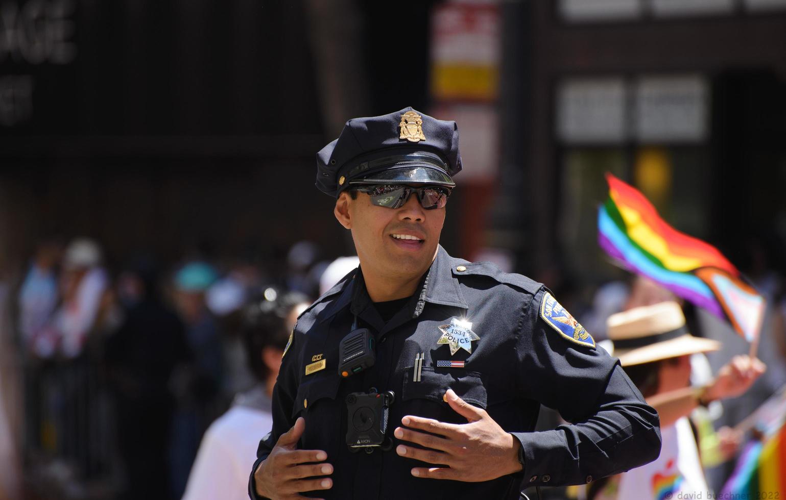 san francisco, ca, usa - 22. juni 2022, stolzparade, san francisco-polizist, der bei der parade mit einer stolzfahne im hintergrund dient foto