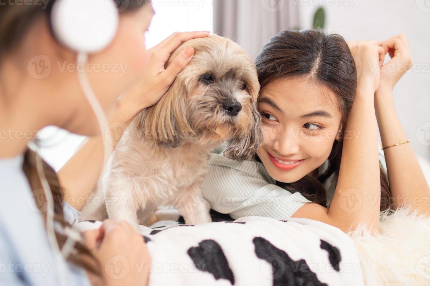 Paar schöne asiatische Freundinnen, die ihren Hund im Karton genießen. foto