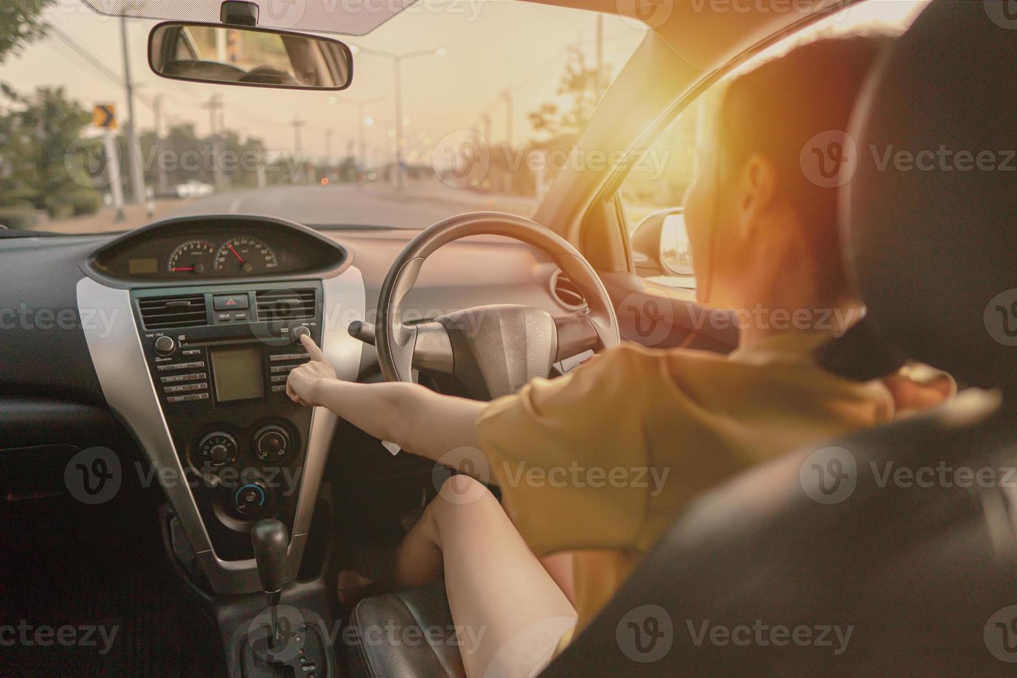 frau fährt auto auf der straße und öffnet radio foto