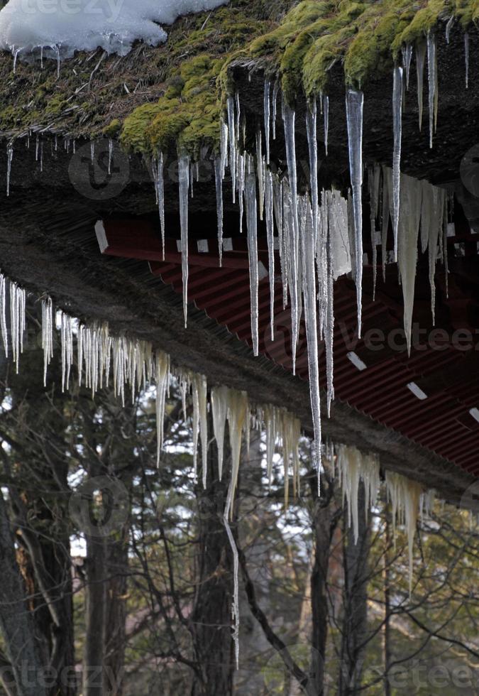 Eiszapfen hängen von einem traditionellen Dach in Kusatsu Onsen, Japan foto