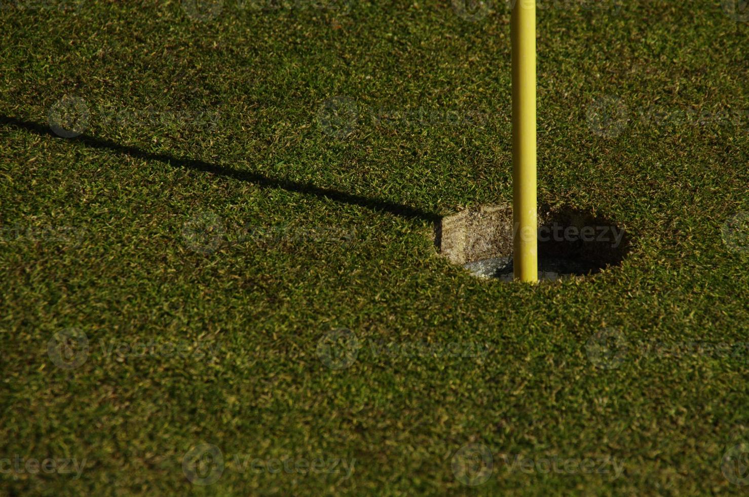 Nahaufnahme von Loch und Fahnenstange auf einem Golfplatz foto