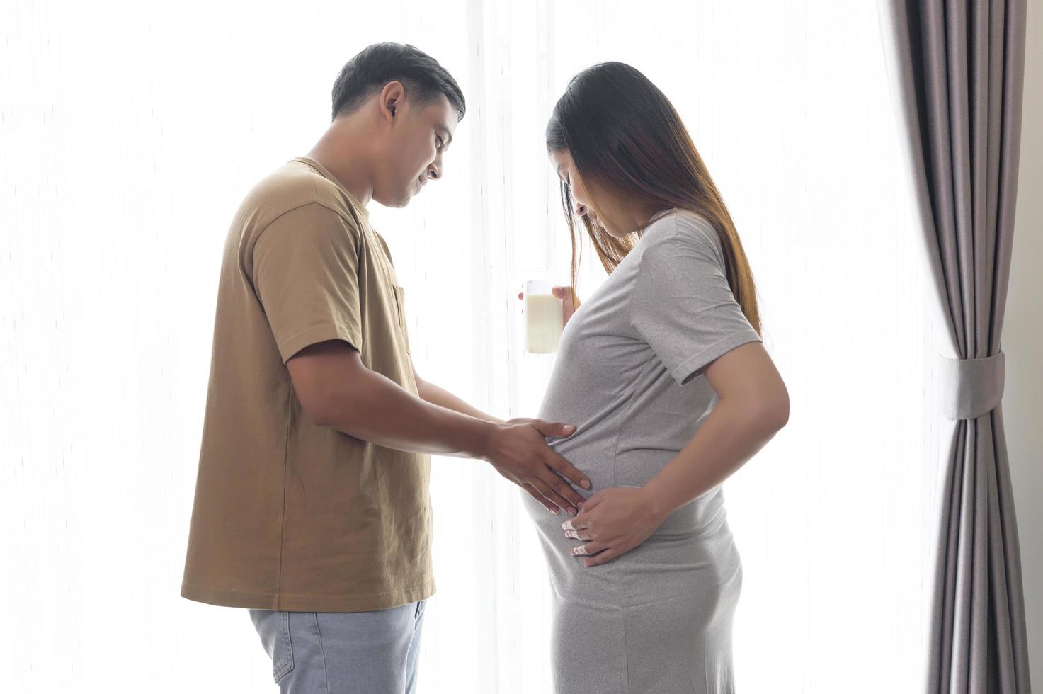 junge schwangere frau, die milch zu hause trinkt, gesundheitswesen und schwangerschaftspflege foto