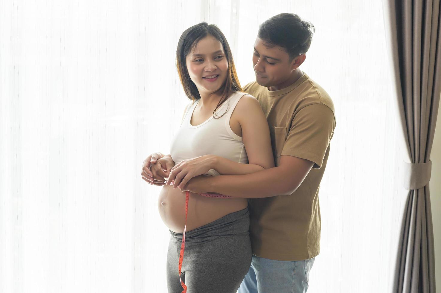 junge schwangere frau, die bauchzentimeter, gesundheitswesen und schwangerschaftspflege misst foto