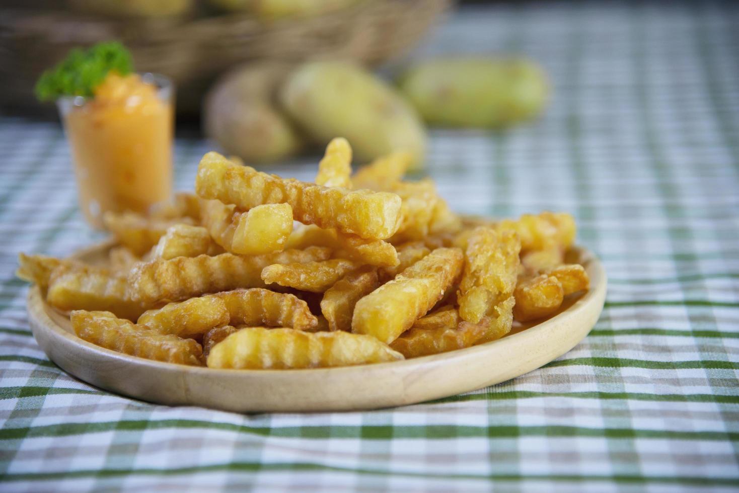 Köstliche Bratkartoffeln auf Holzteller mit eingetauchter Sauce - traditionelles Fast-Food-Konzept foto