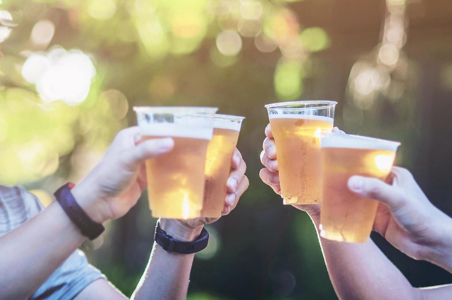 Celebration Beer Cheers Concept - Nahaufnahme von Händen, die während ihres Siegeswettbewerbs oder ihrer erfolgreichen Aufgabenbesprechung Biergläser von Volksgruppen auf Partys im Freien hochhalten foto