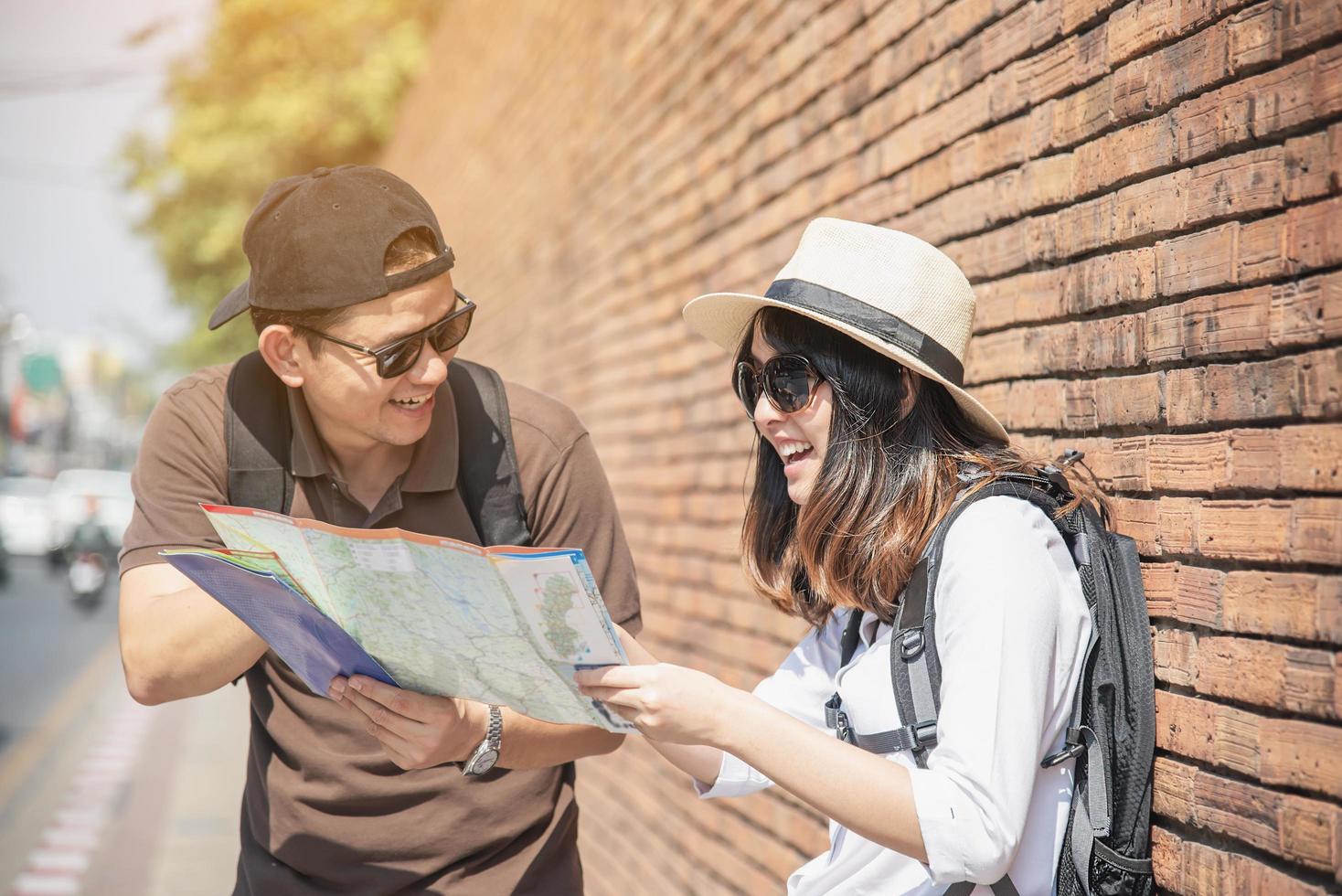 asiatisches rucksackpaar tourist, der stadtplan hält, der die straße überquert - reisen leute urlaub lebensstilkonzept foto